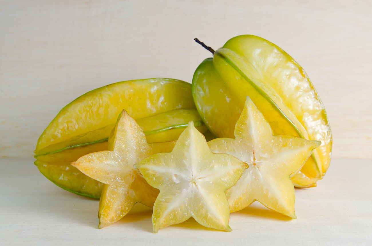 Star apple fruit with half cross section isolated on wooden board Edible Landscape star fruit